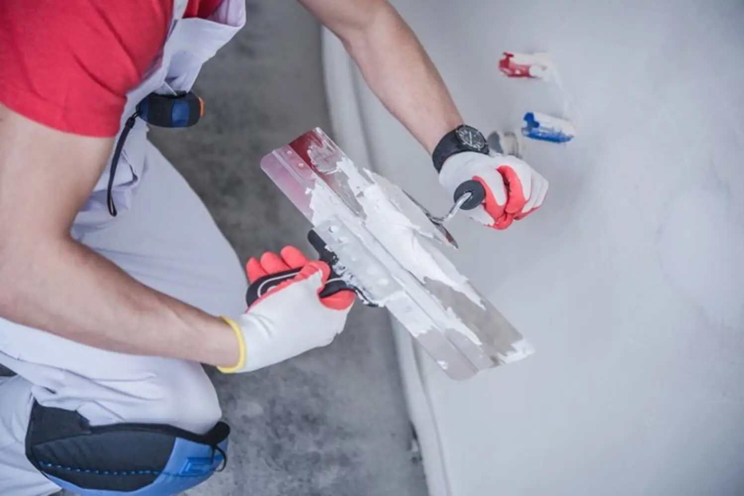 Professional painter applying joint compound to an interior wall during surface preparation, showing how interior painting prep affects the quality of the finish.