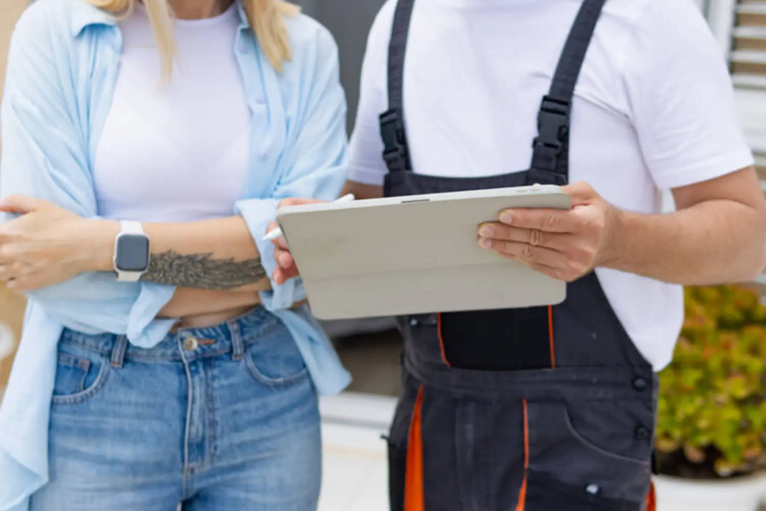 Homeowner and painting contractor reviewing a quote on a tablet outside a home, illustrating how to choose a painting contractor you can trust.