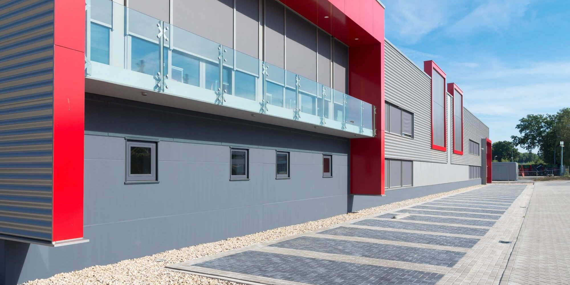 Modern commercial building with grey metal cladding and bold red accent panels, representing commercial painting services in London, Ontario