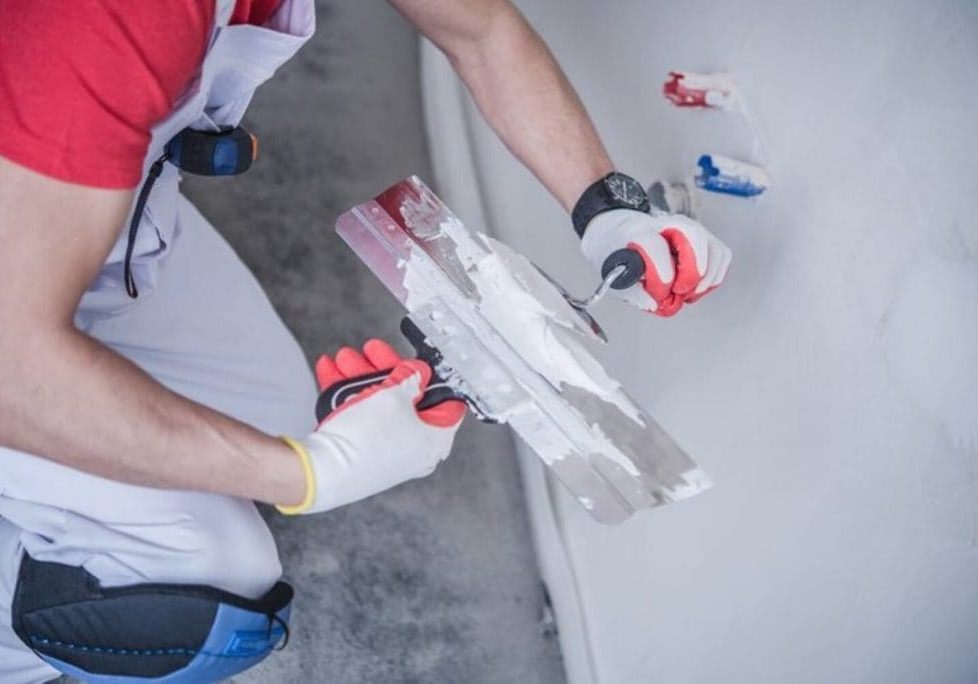 Professional painter applying joint compound to an interior wall during surface preparation, showing how interior painting prep affects the quality of the finish.