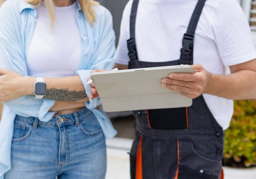 Homeowner and painting contractor reviewing a quote on a tablet outside a home, illustrating how to choose a painting contractor you can trust.